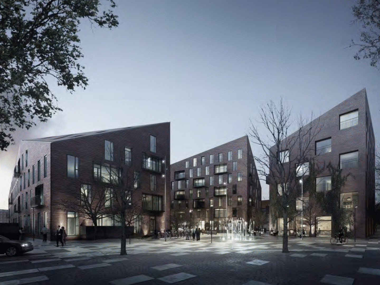 Tre flervåningshus med olika storlek på fönsterna. Kvällstid. En fontän lyser upp kvällen.